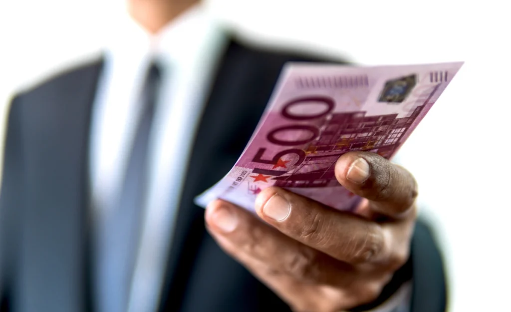 Un homme qui tend des billets de 500 euros