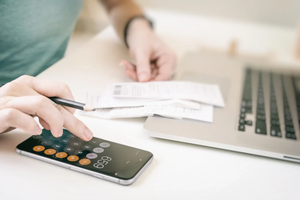 Une personne qui fait des calculs avec un smartphone et des factures